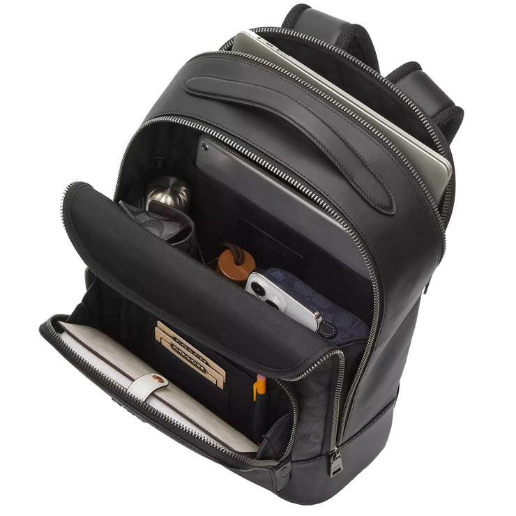Front view of Coach Ethan Backpack Bag In Signature Canvas - Charcoal/ Black CY832, shown with organized contents including tech accessories, documents, water bottle & umbrella