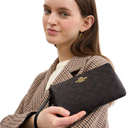 Model Holding Coach Large Corner Zip Wristlet In Signature Canvas - Walnut/ Black CZ277