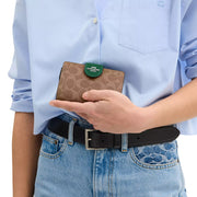 Model View of Coach Medium Corner Zip Wallet In Signature Canvas - Tan/ Shamrock CW786
