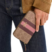 Model Carrying Coach Medium Id Zip Wallet In Signature Canvas With Varsity Stripe - Tan Multi CBO79