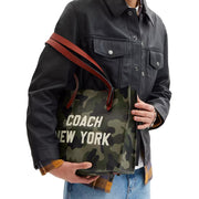 Model Wearing Coach Relay Tote Bag 34 With Camo Print And Coach Graphic - Camo CY811